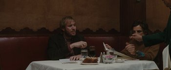 Movie still from “Greenberg” (2010), directed by Noah Baumbach – A man sitting at a table in front of a plate of food; Medium shot, Over the shoulder angle