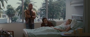 Movie still from “Greenberg” (2010), directed by Noah Baumbach – Two men standing next to each other in front of a hospital bed; Medium shot, Over the shoulder angle