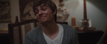 Movie still from “Greenberg” (2010), directed by Noah Baumbach – A young man is smiling while sitting in a chair; Close Up shot, Over the shoulder angle