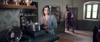 Movie still from “Haider” (2014), directed by Vishal Bhardwaj – A woman standing next to a pot on a stove in a kitchen; Medium shot, Low angle