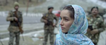 Movie still from “Haider” (2014), directed by Vishal Bhardwaj – A woman wearing a blue headscarf standing in front of a man in fatigues; Close Up shot, Over the shoulder angle