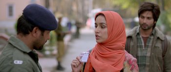 Movie still from “Haider” (2014), directed by Vishal Bhardwaj – A woman wearing a red head scarf holding a card; Close Up shot, Over the shoulder angle
