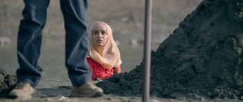 Movie still from “Haider” (2014), directed by Vishal Bhardwaj – A woman in a headscarf is looking at a man in work boots; Wide shot, Over the shoulder angle