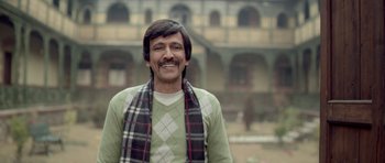 Movie still from “Haider” (2014), directed by Vishal Bhardwaj – A man with long black hair wearing a green sweater and a plaid scarf; Medium shot, Low angle