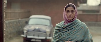 Movie still from “Haider” (2014), directed by Vishal Bhardwaj – A woman with a pink headscarf standing in front of an old car; Close Up shot, Over the shoulder angle