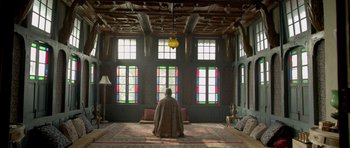 Movie still from “Haider” (2014), directed by Vishal Bhardwaj – A man sitting in a room with stained glass windows; Extreme Wide shot, Low angle