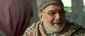 Movie still from “Haider” (2014), directed by Vishal Bhardwaj – An older man wearing a hat and a scarf; Close Up shot, Over the shoulder angle