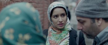 Movie still from “Haider” (2014), directed by Vishal Bhardwaj – A woman wearing a colorful headscarf standing on a sidewalk; Close Up shot, Over the shoulder angle