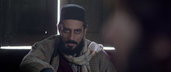 Movie still from “Haider” (2014), directed by Vishal Bhardwaj – A man with a beard wearing a hat and a scarf; Close Up shot, Over the shoulder angle