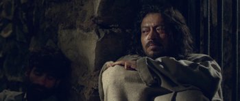 Movie still from “Haider” (2014), directed by Vishal Bhardwaj – A man with long hair and a beard laying in a cave; Close Up shot, High angle