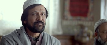 Movie still from “Haider” (2014), directed by Vishal Bhardwaj – A man with a beard wearing a white hat; Close Up shot, Low angle