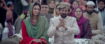 Movie still from “Haider” (2014), directed by Vishal Bhardwaj – A man and a woman sitting next to each other in front of a group of people; Medium shot, Low angle