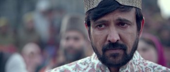 Movie still from “Haider” (2014), directed by Vishal Bhardwaj – A person with a beard wearing a hat; Close Up shot, Over the shoulder angle