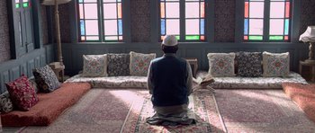 Movie still from “Haider” (2014), directed by Vishal Bhardwaj – A man sitting on the floor in front of stained glass windows; Wide shot, High angle