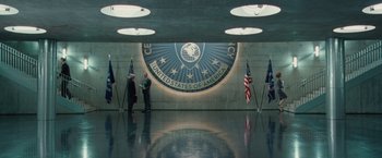 Movie still from “Hanna” (2011), directed by Joe Wright – A group of people standing in front of an american flag; Wide shot, Low angle