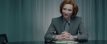 Movie still from “Hanna” (2011), directed by Joe Wright – A woman sitting at a table in front of papers; Medium shot, Over the shoulder angle