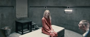 Movie still from “Hanna” (2011), directed by Joe Wright – A woman sitting on top of a bench in a jail cell; Wide shot, High angle