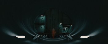 Movie still from “Hanna” (2011), directed by Joe Wright – A person in an orange suit is standing in a dark room; Extreme Wide shot, High angle