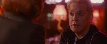 Movie still from “Hanna” (2011), directed by Joe Wright – A man sitting in front of another man in front of a lamp; Close Up shot, Over the shoulder angle