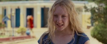 Movie still from “Hanna” (2011), directed by Joe Wright – A young girl with blonde hair smiling for the camera; Close Up shot, Over the shoulder angle