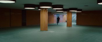 Movie still from “Hanna” (2011), directed by Joe Wright – A man is walking in a hallway with pillars; Extreme Wide shot, High angle