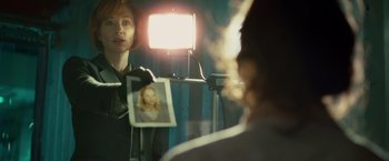 Movie still from “Hanna” (2011), directed by Joe Wright – A woman holding up a picture in front of a mirror; Close Up shot, Over the shoulder angle