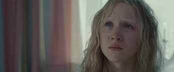 Movie still from “Hanna” (2011), directed by Joe Wright – A woman with long blonde curly hair looking out a window; Close Up shot, Over the shoulder angle
