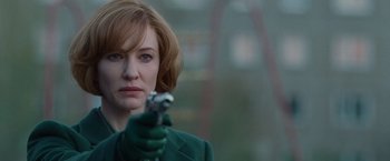 A woman in a green coat holding a gun