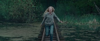 Movie still from “Hanna” (2011), directed by Joe Wright – A woman walking across a bridge in the middle of a river; Medium shot, High angle
