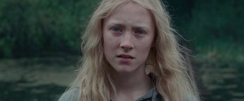 Movie still from “Hanna” (2011), directed by Joe Wright – A woman with long blonde hair and blue eyes looking at the camera; Close Up shot, Over the shoulder angle
