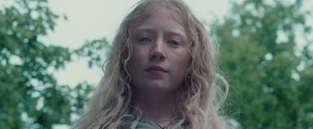 Movie still from “Hanna” (2011), directed by Joe Wright – A woman with long blonde curly hair wearing a green shirt; Close Up shot, Low angle