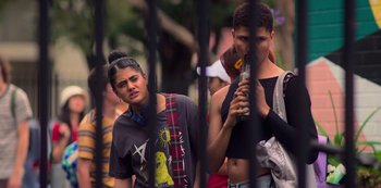 Movie still from “Heartbreak High” (2022), created by Michael Jenkins – A group of people standing next to each other near a fence; Medium shot, Over the shoulder angle