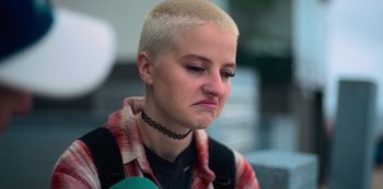 Movie still from “Heartbreak High” (2022), created by Michael Jenkins – A woman with a shaved head is looking down at her face; Close Up shot, Low angle