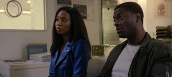 Movie still from “Black Mirror” (2011), created by Charlie Brooker – A woman and a man sitting next to each other in a room; Medium shot, Over the shoulder angle