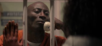 Movie still from “Black Mirror” (2011), created by Charlie Brooker – A man in an orange shirt is looking in the mirror; Close Up shot, High angle