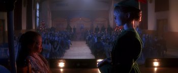 Movie still from “Hook” (1991), directed by Steven Spielberg – A woman standing in front of an audience in front of a stage; Wide shot, Low angle