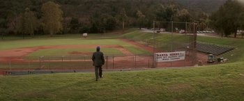 Movie still from “Hook” (1991), directed by Steven Spielberg – A man walking across a grass covered baseball field; Extreme Wide shot, High angle