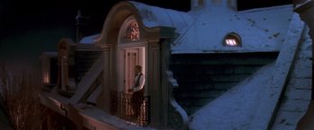 Movie still from “Hook” (1991), directed by Steven Spielberg – A man standing on a porch of a building at night; Wide shot, Low angle