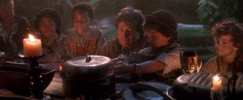 Movie still from “Hook” (1991), directed by Steven Spielberg – A woman and two children cutting a cake on top of a table; Medium shot, High angle