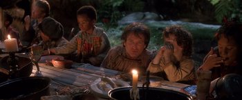 Movie still from “Hook” (1991), directed by Steven Spielberg – A group of people sitting at a table with a lit candle; Medium shot, High angle