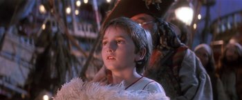 Movie still from “Hook” (1991), directed by Steven Spielberg – A young girl wearing a white dress and a white feather boa; Close Up shot, Over the shoulder angle