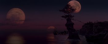 A full moon setting over the ocean with a ship in the distance