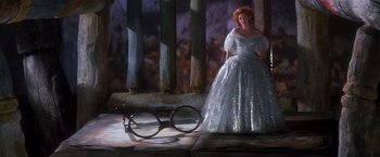 Movie still from “Hook” (1991), directed by Steven Spielberg – A woman in a silver dress standing next to a pair of glasses; Wide shot, High angle