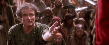 Movie still from “Hook” (1991), directed by Steven Spielberg – A group of people in a room with a man in a green shirt pointing; Close Up shot, Low angle