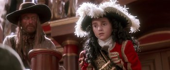 Movie still from “Hook” (1991), directed by Steven Spielberg – A young girl in a pirate costume with a white feather headdress; Close Up shot, Over the shoulder angle