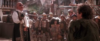 Movie still from “Hook” (1991), directed by Steven Spielberg – A group of people in costumes walking down a street; Medium shot, Over the shoulder angle