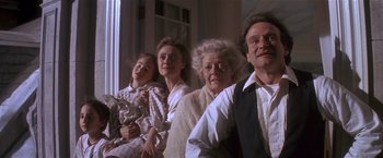 Movie still from “Hook” (1991), directed by Steven Spielberg – A group of people that are sitting in front of a window; Medium shot, Low angle
