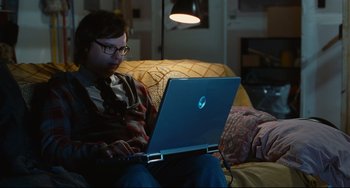 Movie still from “Hot Tub Time Machine” (2010), directed by Steve Pink – A man sitting on a couch using a laptop computer; Medium shot, High angle