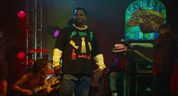 Movie still from “Hot Tub Time Machine” (2010), directed by Steve Pink – A man in a black shirt is standing in front of a band; Medium shot, Over the shoulder angle