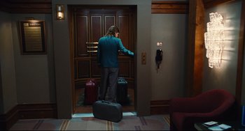 Movie still from “Hot Tub Time Machine” (2010), directed by Steve Pink – A man standing in front of two suitcases in front of a door; Wide shot, High angle